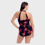 Rear view of a woman modeling a navy one-piece swimsuit with red and pink floral print, featuring a racerback design and gold halter clasp at the neck.