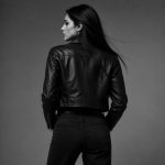 Women's black leather biker jacket model back view B&W studio, clean rear construction, zip cuffs, cropped length