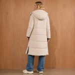 Women's cream longline puffer jacket model back view, hood, clean rear construction, side slit, mid-thigh length