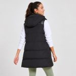 Women's black puffer vest model back view, hood, clean rear construction, long length