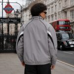 Men's windbreaker in grey with white panels and black piping, model back view London Westminster urban lifestyle