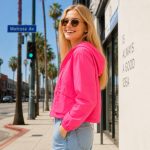 Women's hot pink windbreaker hoodie model side profile walking, full zip, drawcord hood