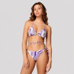 Women's purple and green abstract swirl print bikini set model front view studio against plain white background, triangle halter top with long wrap-around waist ties, side-tie bottom, gold belly chain accessory