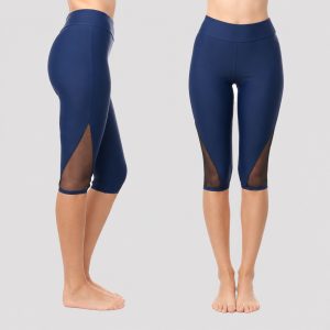 Women's plus-size navy high-waist capri swim leggings with wide elastic waistband, mid-calf length, black mesh inset panel at outer calf, V-cut hem, opaque stretch fabric