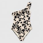 Women's one-piece swimsuit in black with cream floral leaf print, flat lay front view, one-shoulder ruffle trim detail, low-rise leg cut