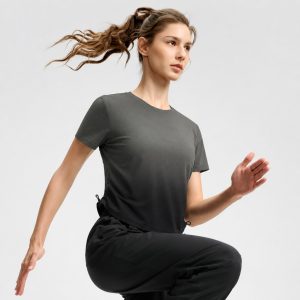 Women's athletic workout top in black ombre gradient (dark grey at neck fading to black at hem) with side drawstring ruching - model front view, OEM wholesale women's activewear, sizes XS-XL