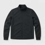 Lay-flat product shot of black mock-neck full-zip athletic jacket, two side slash hand pockets, ribbed cuffs, ribbed hem band, light gray backdrop