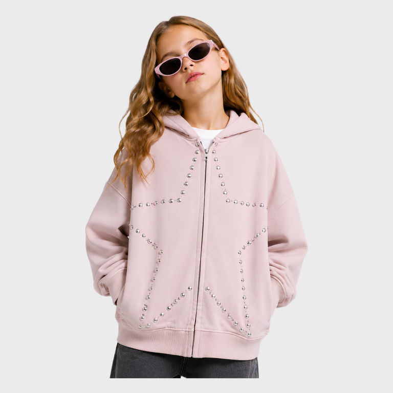 Young girl wearing pink cat-eye sunglasses, front view of dusty pink zip-up hooded sweatshirt with silver stud star design and front pockets.