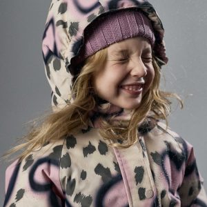 Young child wearing a pink and black leopard-print hooded rain jacket with a mauve knit beanie, smiling with eyes closed in a snowy outdoor setting.