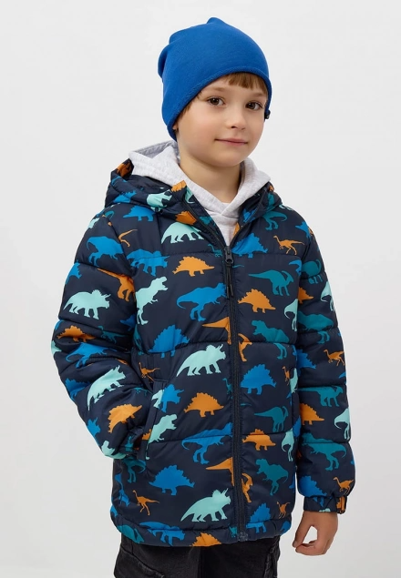 Child's front-facing studio shot wearing a navy puffer jacket with colorful dinosaur print, front zipper, attached hood over gray sweatshirt, paired with blue knit beanie.