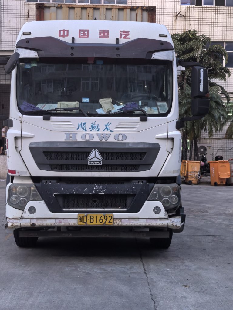 Bulk Apparel Production Completed and Ready for Overseas Shipment 2 HOWO cargo truck positioned at the loading bay at Quanzhou Northern Garment's production facility in Jinjiang, prepared to collect finished bulk apparel for overseas shipment.