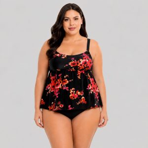 Women's plus-size black tankini top with red, orange, pink, and yellow floral print, scoop neck, wide adjustable straps, empire waist ruffle hem, matching black brief, model front view