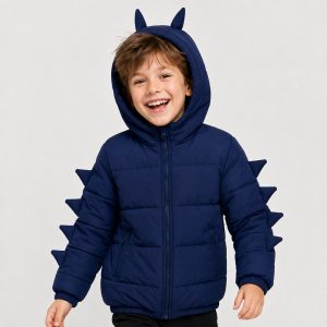 Boy's navy blue puffer jacket back view, hood with two dinosaur horns on top, four 3D triangular fabric dinosaur spikes running down each sleeve outer seam, ribbed hem band, horizontal quilted construction, kid model back view with brown hair, no text or logo