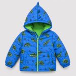 Boy's royal blue diamond quilted puffer jacket flat lay product photo front, hood up with 3D fabric dinosaur spike/horn on hood edge, full-length lime green metal zipper, two zip pockets at front waist, allover scattered cartoon dinosaur silhouette print and 'WILD ONE' slogan and lightning bolt decorations, contrasting lime green inner lining visible at hood interior, ribbed cuffs and hem, clean light gray background for B2B catalog