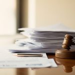 Stack of compliance paperwork and EU regulatory documents on wooden desk