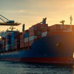 Cargo ship at a European port with stacked containers, autumn lighting.