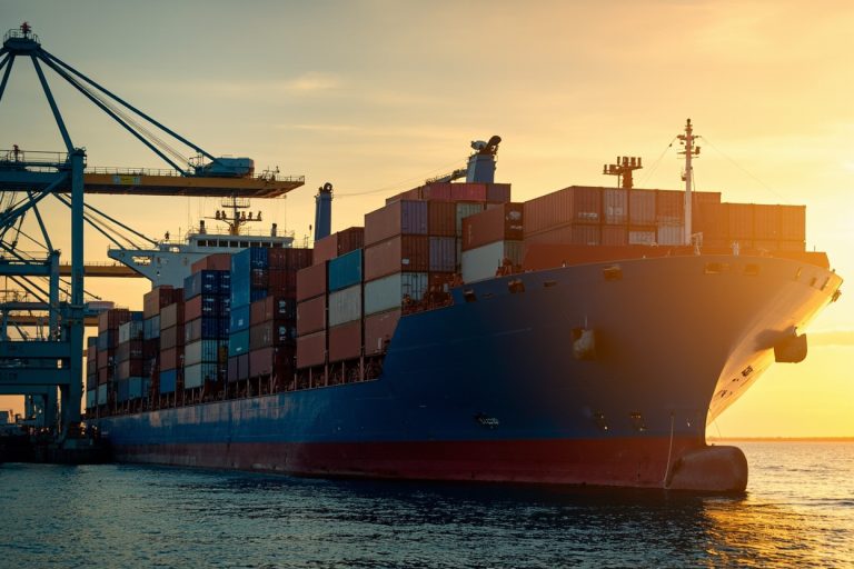 Cargo ship at a European port with stacked containers, autumn lighting.