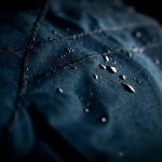 Water droplets beading on a technical outerwear fabric, hydrophobic coating visible.