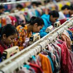 Garment factory production line with workers sewing children's outerwear, organized workstations.