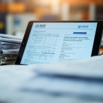 Stacked shipping paperwork with a digital tablet displaying customs forms, freight forwarding office setting.
