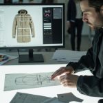 Designer reviewing jacket tech pack and CAD pattern drawings